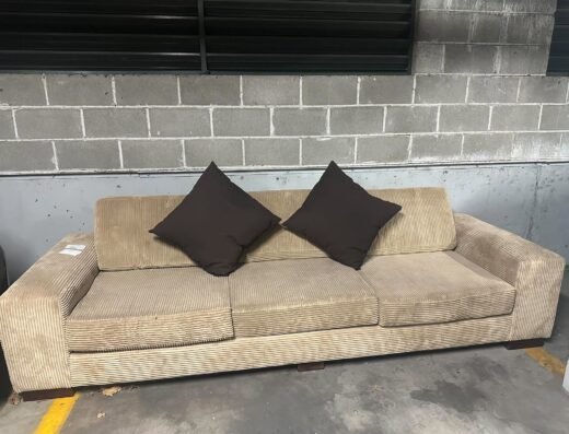 Beige three-seater sofa with two dark brown cushions